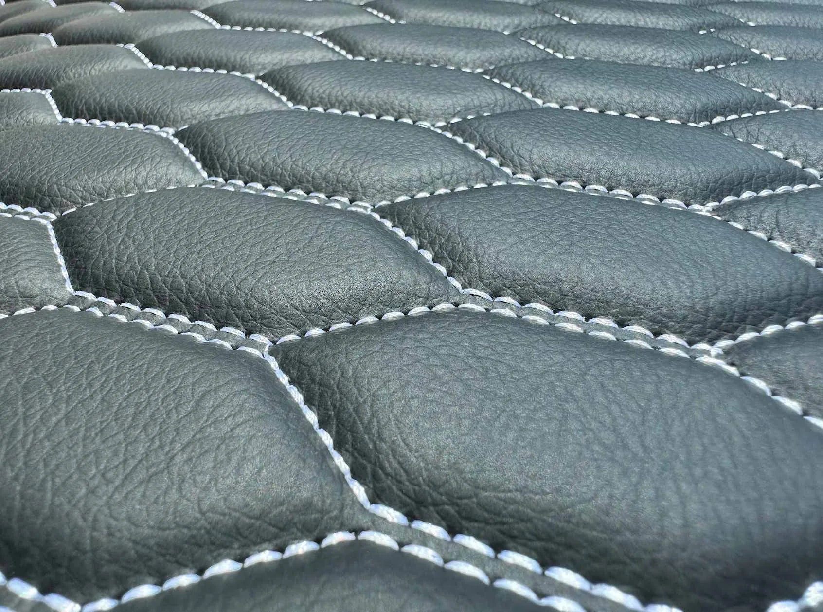 Close-up of Omnicore 14 eco-leather with a natural grain and white honeycomb stitching
