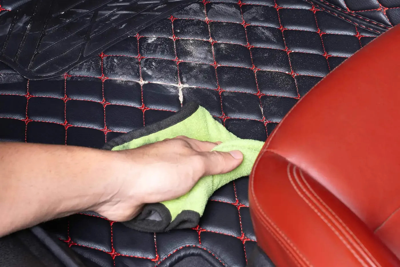 Hand wiping sand off a Luxus mat with a microfiber towel