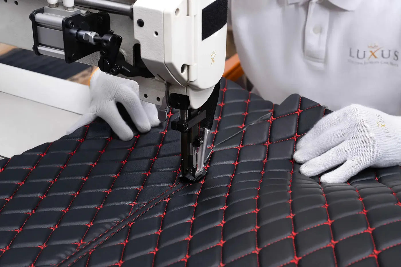 Luxus craftsman in white gloves stitching a black mat with red diamond stitching